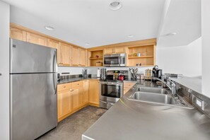 A modern kitchen with stainless steel appliances, wooden cabinets, and a double sink.