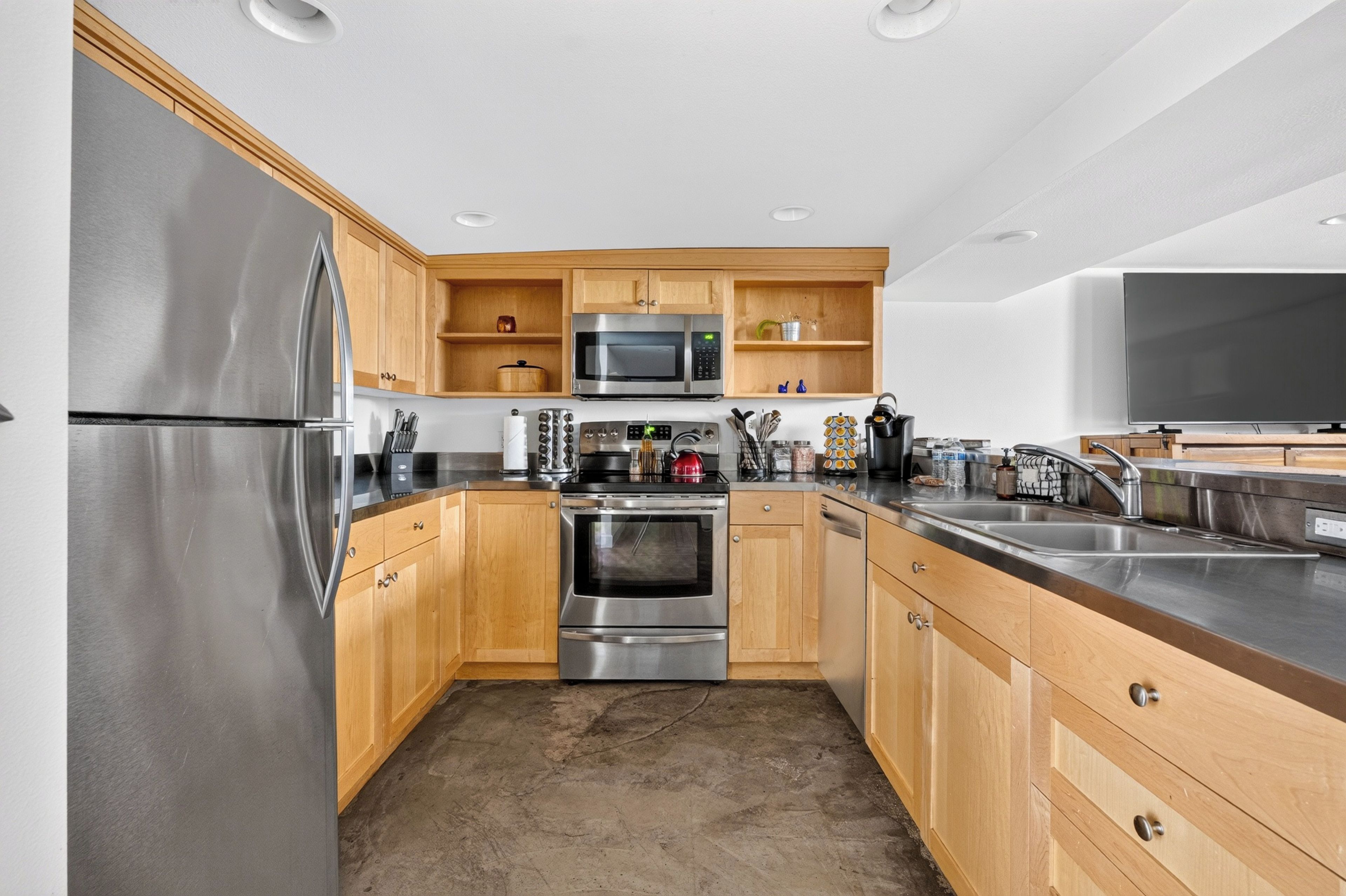 A modern kitchen with stainless steel appliances, wooden cabinets, and a large island with a sink.