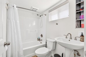 Bathroom with bathtub, shower, and pedestal sink.