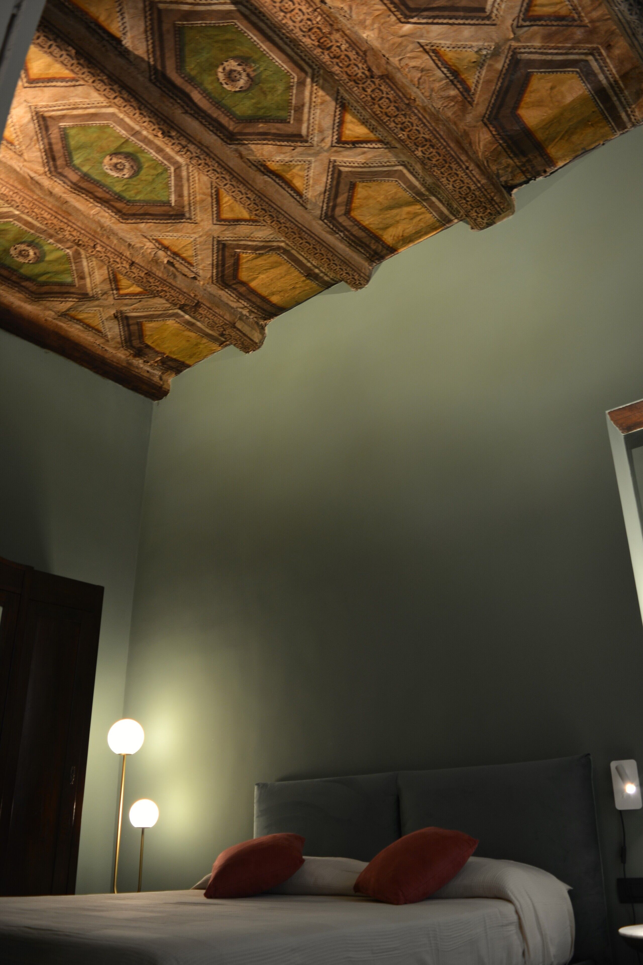 Une chambre à coucher avec un plafond décoré, un lit avec des oreillers et des lampes de chevet.