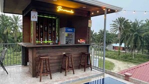 Zona de bar con un letrero de neón, una bomba de gasolina GRS y vista a la piscina.