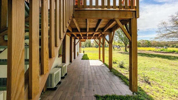A wooden deck with a covered walkway leading to a grassy area. - Le Grenier in a magnificent forest park on the edge of the lake 8km to the ocean (Aureilhan)