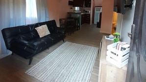 Una sala de estar con un sofá de cuero negro, un tapete blanco y un ventilador de techo.