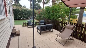 A patio with a wooden fence, outdoor furniture, and a view of a garden with trees and bushes. - Spatieux Mobile Home DE 40m2 + Terrasse (Hyères)