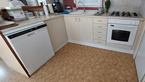 A compact kitchen with a dishwasher, oven, sink, and gas stove. - Spatieux Mobile Home DE 40m2 + Terrasse (Hyères)