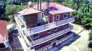 A multi-story building with a red roof, a balcony on the upper floor, and a sign with text.
