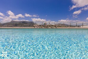 A clear pool with lounge chairs and a table, surrounded by mountains and a clear sky. - Villa ALEGRANZA by Abahana Villas (Calpe)