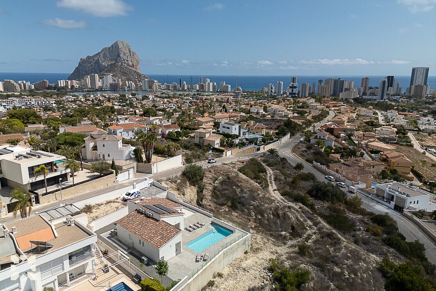 A coastal cityscape with a prominent mountain, modern buildings, and a swimming pool area.