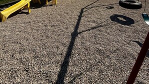 A playground with a yellow slide and swings, set against a backdrop of trees and mountains. - Quaint Riverside Cabin # 1 (Crowsnest Pass)
