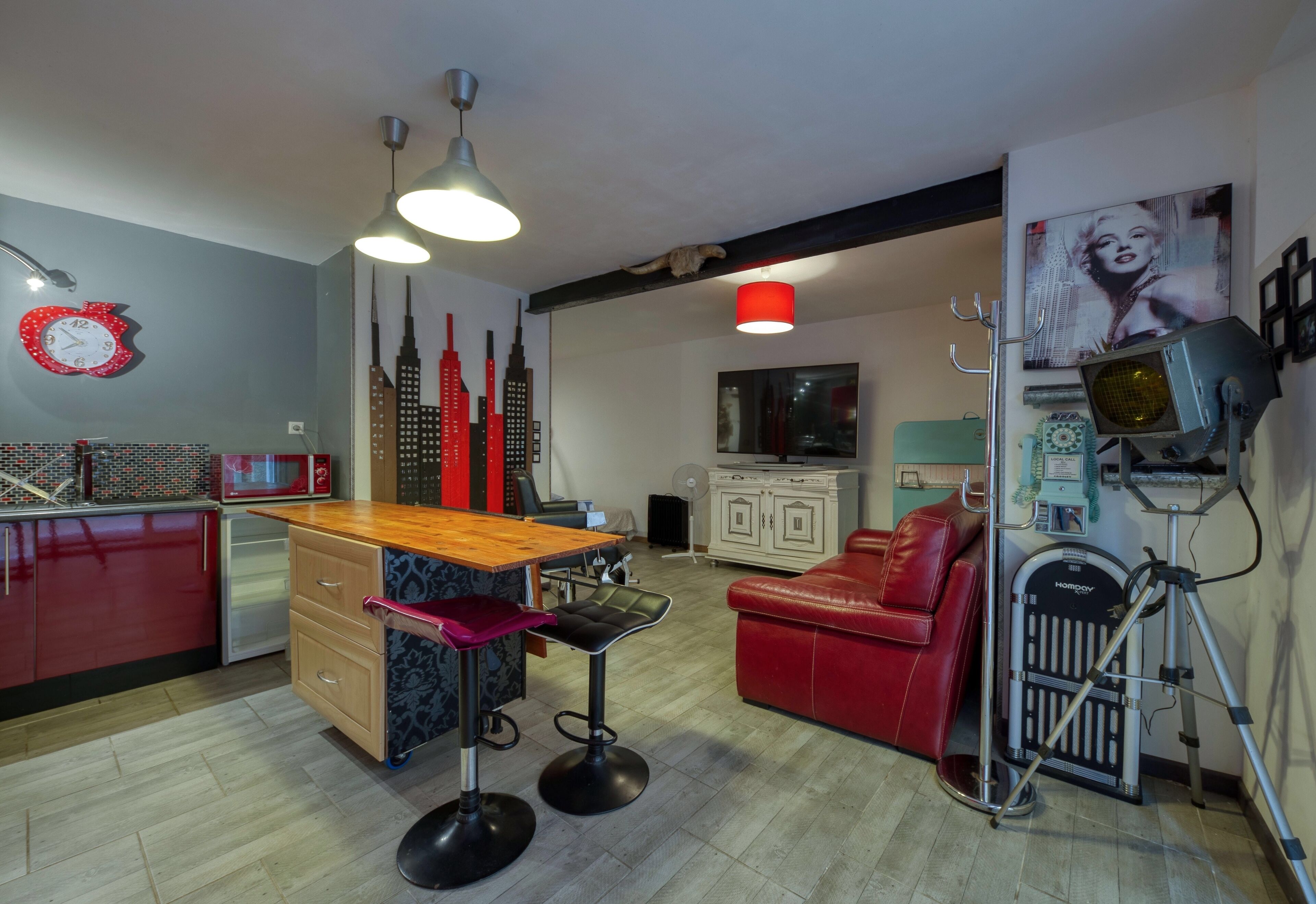 A modern kitchen with a wooden countertop, bar stools, and a red leather couch.