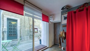 A room with a sliding glass door leading to a courtyard, a red curtain, and a mounted air conditioning unit.