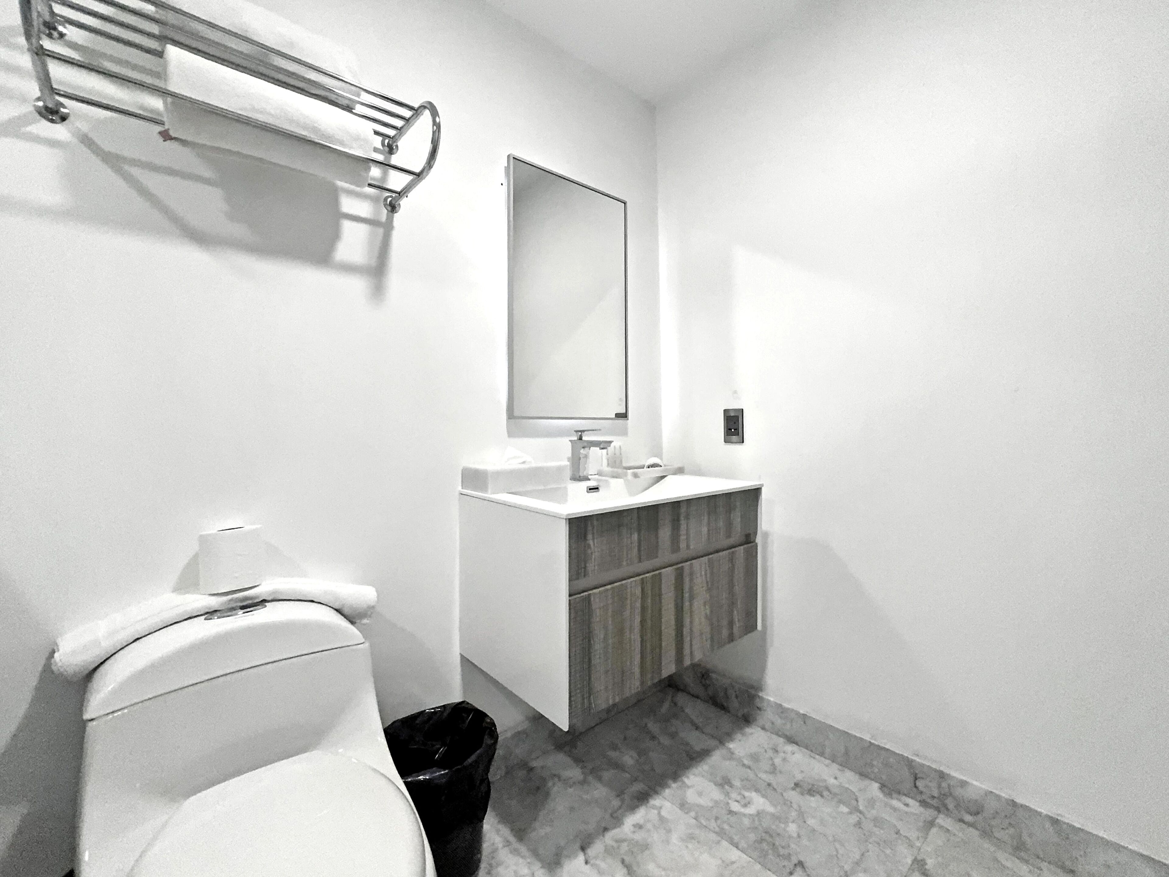 Ein Badezimmer mit Toilette, Waschbecken, Spiegel und Handtuchhalter.