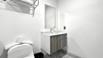 Ein Badezimmer mit Toilette, Waschbecken, Spiegel und Handtuchhalter.
