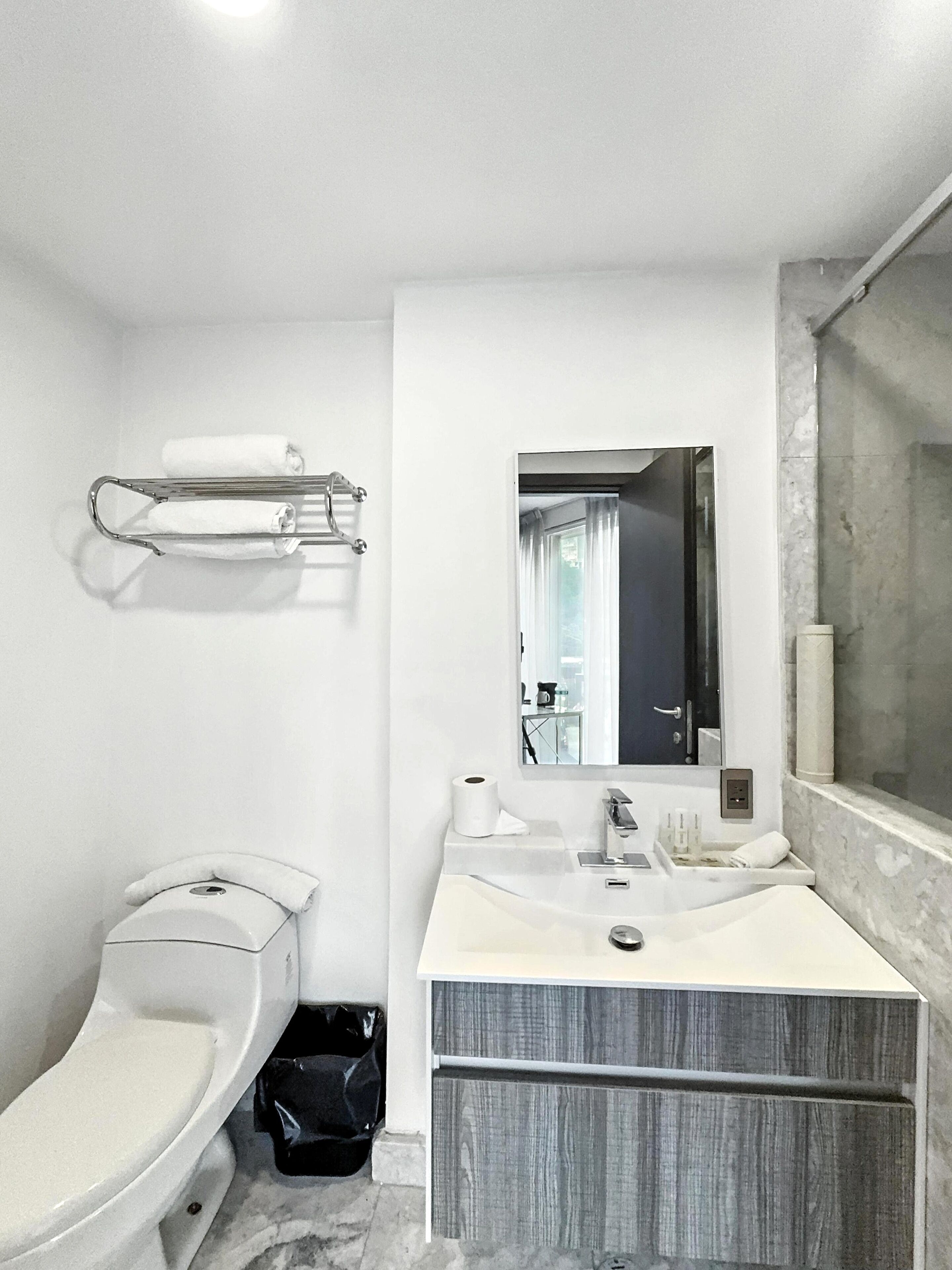 Ein modernes Badezimmer mit Toilette, Waschbecken, Spiegel und Dusche.