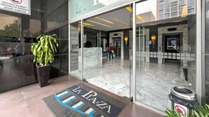 The entrance of La Pazza with a glass door, a potted plant, and a doormat with the hotel's name. - Elite 47 Unity (Huixquilucan)