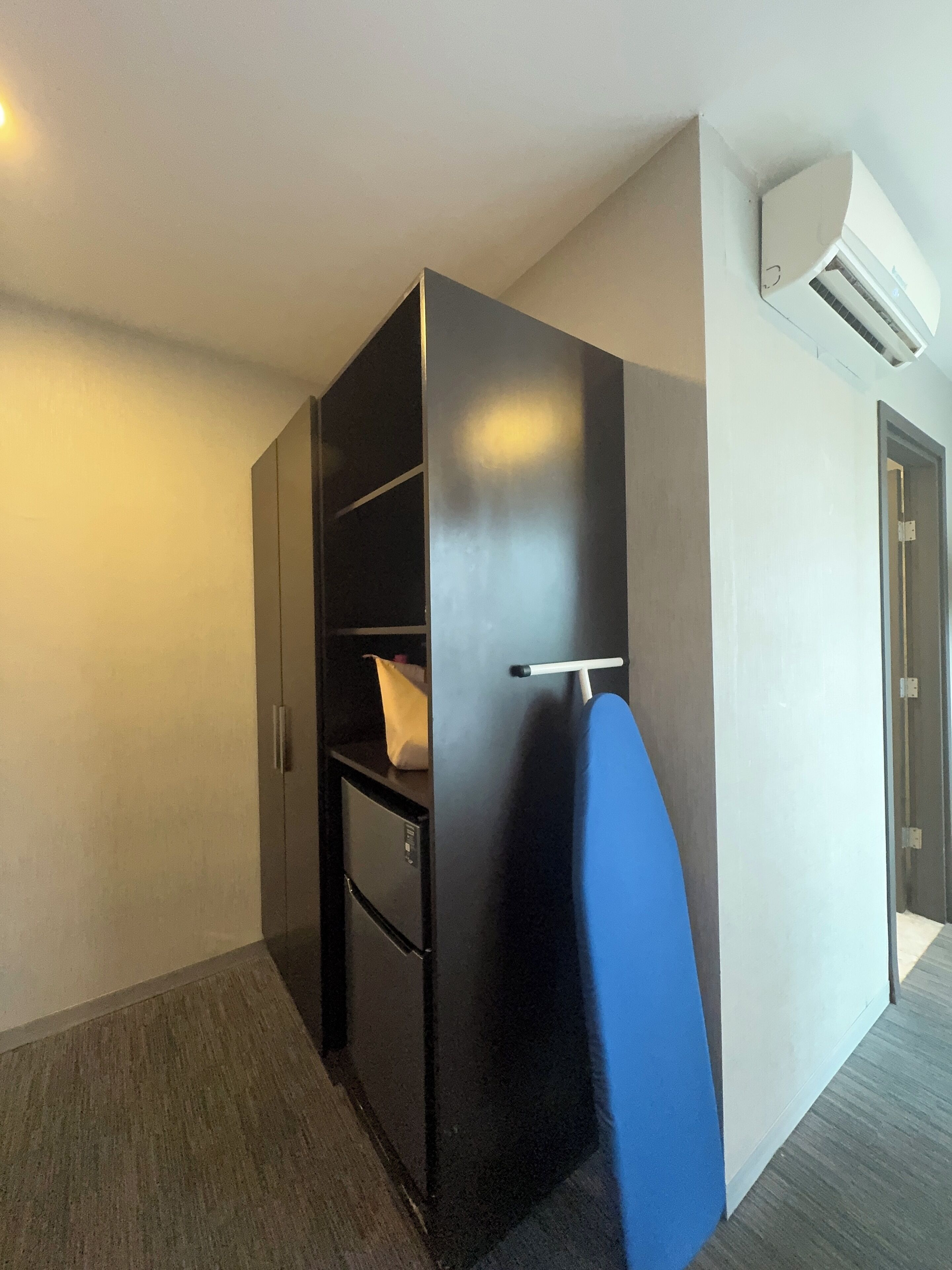 Habitación pequeña con armario empotrado, kitchenette y una puerta que da a otra habitación.