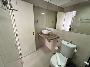 A bathroom with a white toilet, a wooden vanity with a sink, and a mirror above the sink. - Piscina AC vaga Itaim Brazilian Corner (São Paulo)