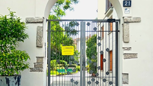 A gated entrance with a sign indicating a service area, a number 21 sign, and a potted plant. - Lovely Flat - Magolfa 21 (Milan)