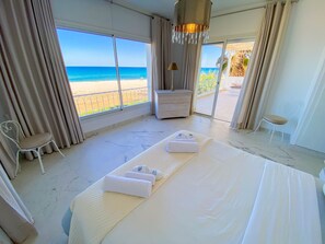 Une chambre d’hôtel avec un grand lit, une table de chevet, une chaise et une vue sur la plage.