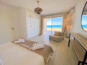 Une chambre d’hôtel avec un lit, un canapé, un bureau et vue sur la plage.