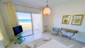 A hotel room with a bed, a TV, a desk, and a view of the beach. - The Luxury Sea House in Hammamet (Hammamet)