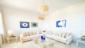 A modern living room with a white sectional sofa, a glass coffee table, and a chandelier. - The Luxury Sea House in Hammamet (Hammamet)