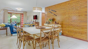 Een eetgedeelte met een grote tafel en stoelen, een houten wand met vleermuisdecoraties en een hanglamp.