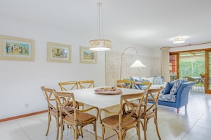 Uma sala de jantar com mesa redonda, cadeiras de madeira e duas luminárias pendentes.