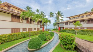 Een resort met een zwembad, palmbomen en uitzicht op de oceaan.