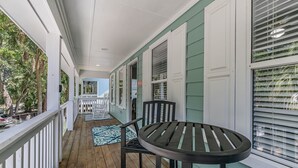 A covered porch with a wooden floor, white railings, and a table with chairs. - Golf cart included, amenity cards available, pet friendly - great for young families, 601 Porpoise Circle (Fripp Island)