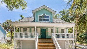A two-story house with a green door, white railings, and a wooden staircase leading to the front porch. - Golf cart included, amenity cards available, pet friendly - great for young families, 601 Porpoise Circle (Fripp Island)