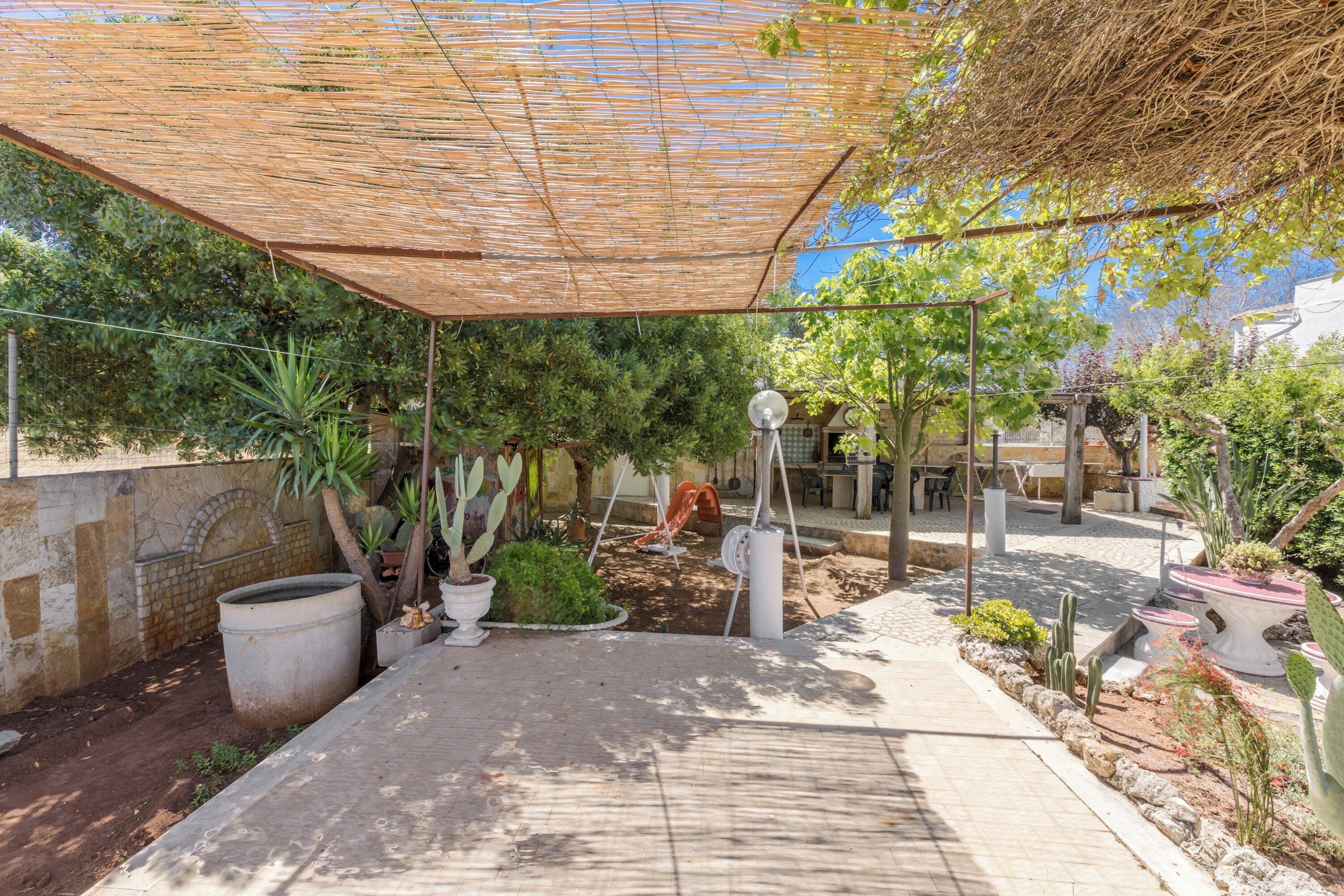 Un patio techado al aire libre con plantas en macetas, una zona de estar y una pared de piedra.