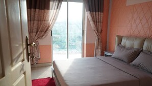 Een slaapkamer met een bed, gordijnen en uitzicht door een glazen deur.