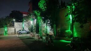 Een buitenruimte 's nachts met groene verlichting, een geparkeerde auto en buitenmeubilair.