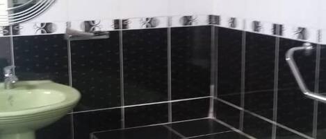 A bathroom with a green sink, a bathtub, and black and white tiled walls.