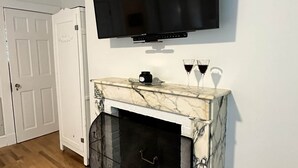 A living room with a fireplace, a mounted television, and a patterned rug. - Arden Cottage (Mount Vernon)
