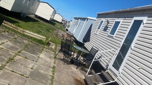 A row of mobile homes with a paved patio area in the foreground. - Coastal Cabin Retreat in Rhyl (Rhyl)