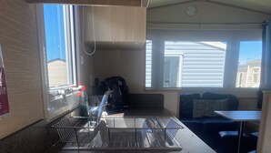 A kitchen with a stainless steel sink, a coffee maker, and a window providing natural light. - Coastal Cabin Retreat in Rhyl (Rhyl)