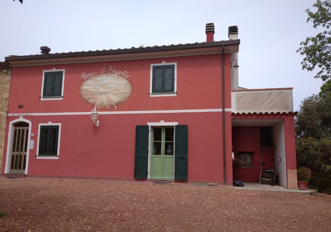 A two-story building with a red facade, green shutters, and a sign that reads "Soddisfatto il Bocconcino."