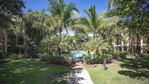 Un resort con piscina rodeada de palmeras y césped cuidado.