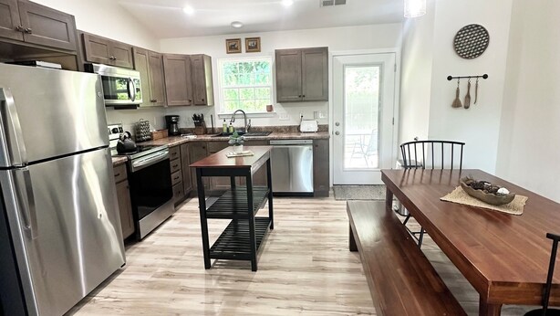 A modern kitchen with stainless steel appliances, a wooden dining table, and a bench.