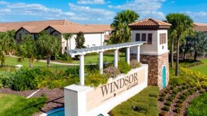 A residential area with a pool, a sign reading "Windsor," and houses with red-tiled roofs. - Free Water Park Private Pool and Lakeview (Kissimmee)