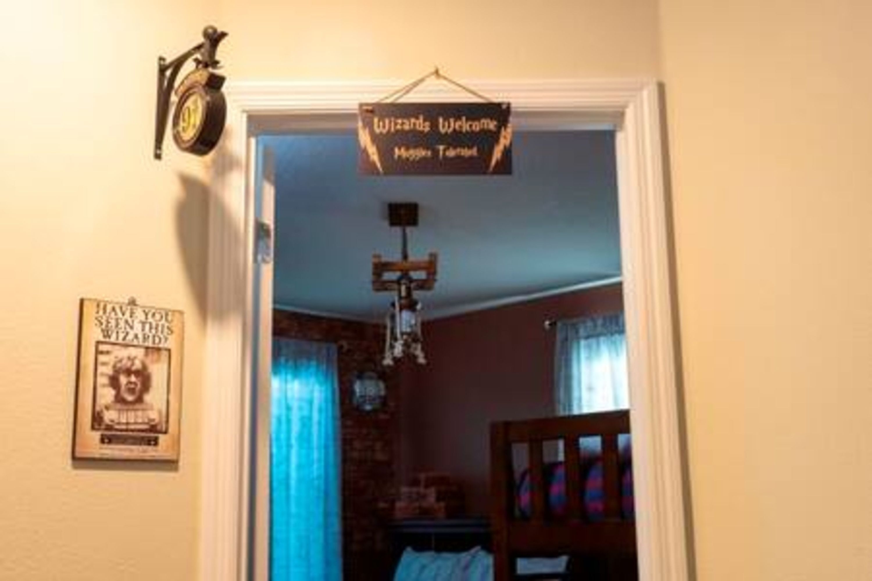 A room with a 'Wizards Welcome' sign, a clock, and a poster on the wall.