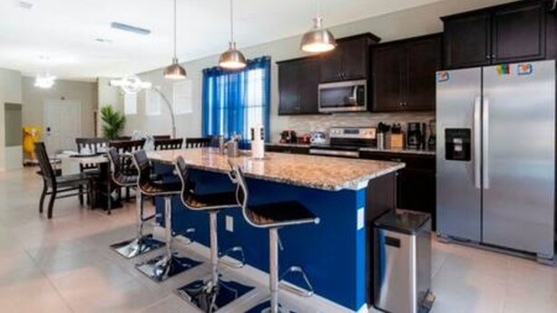 Una cocina moderna con gabinetes oscuros, electrodomésticos de acero inoxidable y una pared de acento azul.