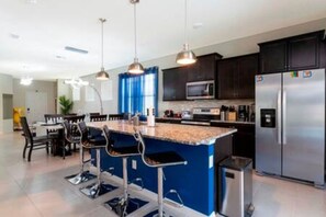 A modern kitchen with dark cabinets, stainless steel appliances, and a blue accent wall. - Free Water Park Windsor Island 5BD - 5BA (Davenport)
