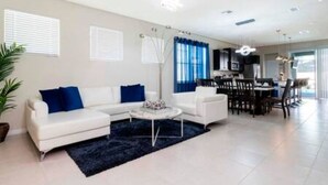 Una sala de estar moderna con un sofá blanco, una mesa de centro y un comedor con mesa y sillas.