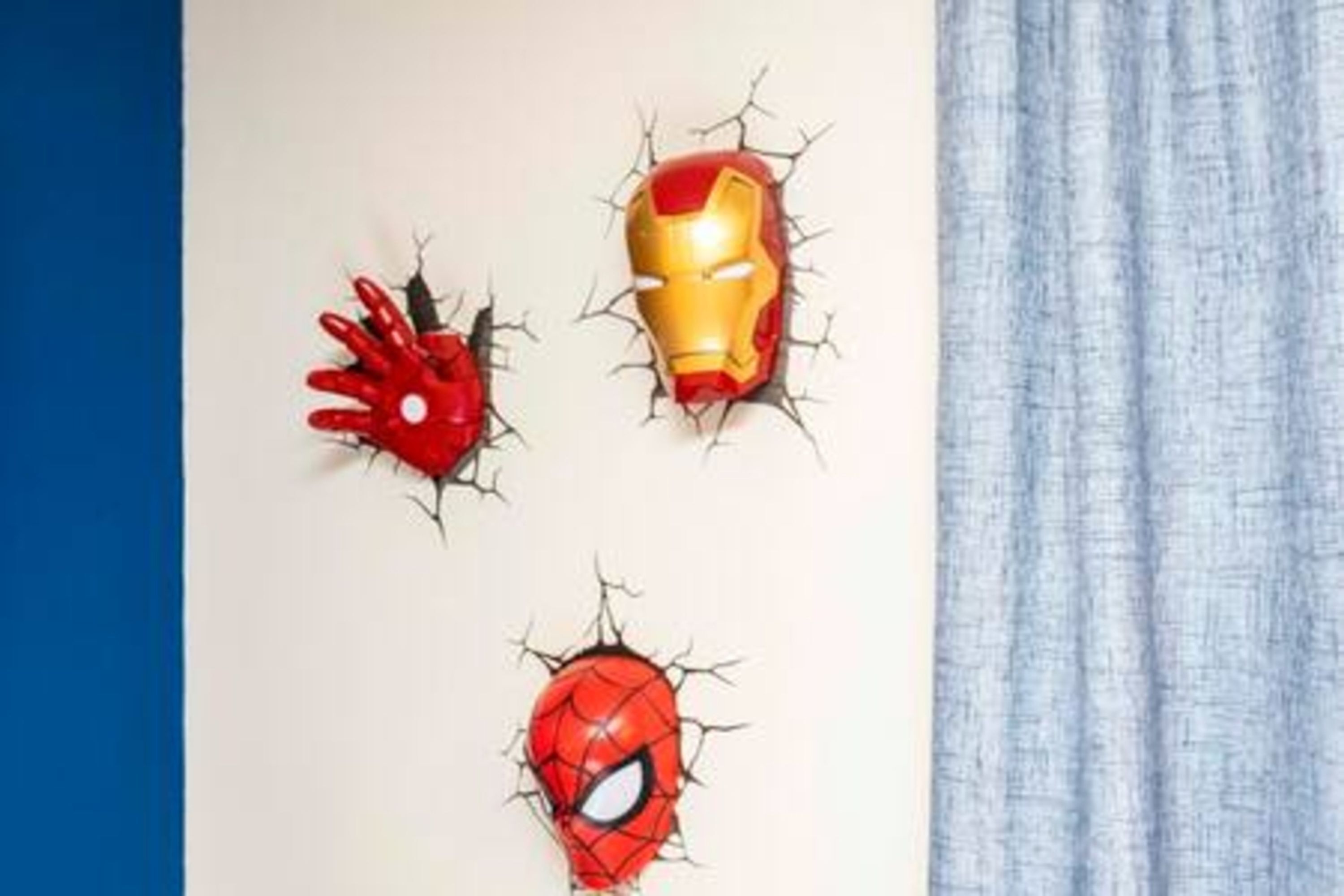 Three superhero masks on a wall.