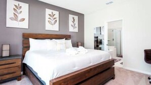 Un dormitorio con una cama de madera, ropa de cama blanca y tres piezas decorativas con motivos de hojas.