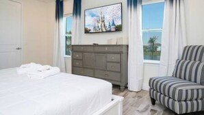 Quarto com cama, penteadeira, cadeira e janela com cortinas.