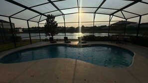 A covered swimming pool with a view of the sunset over a body of water. - 5 Suites - Game Room Theater Room Private Pool (Kissimmee)